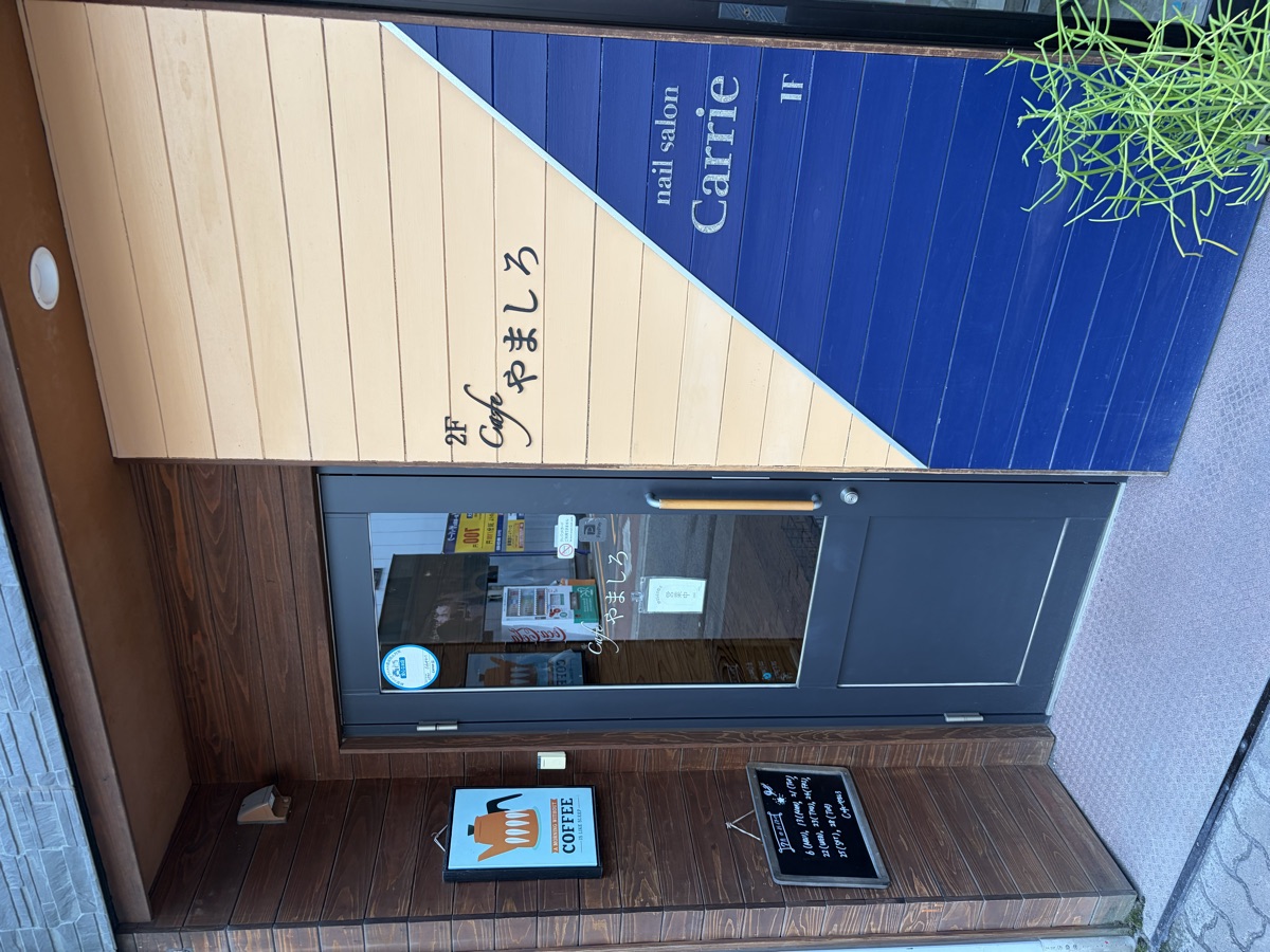 Cafe やましろの入口。木目とネイビーの外観で、カフェはビルの2階